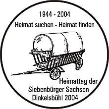 Von schillernder Symbolkraft: Fluchtwagen auf silbernem Hintergrund. Das Abzeichen des Heimattags 2004 setzt das diesjhrige Motto "Heimat suchen - Heimat finden" in optisch ansprechender Gestaltung um. Zwischen dem 28. und 30. Mai werden verschiedene Veranstaltungen in Dinkelsbhl die Flucht und Evakuierung aus Nordsiebenbrgen vor 60 Jahren thematisieren. Zum 270. Mal jhrt sich berdies die zwangsweise Umsiedlung ("Transmigration") evangelischer Landler unter Maria Theresia aus sterreich nach Siebenbrgen. Der Erwerb dieses dekorativen Abzeichens (Preis: 7 Euro) berechtigt zum Besuch smtlicher Heimattagsveranstaltungen des Pfingstwochenendes.