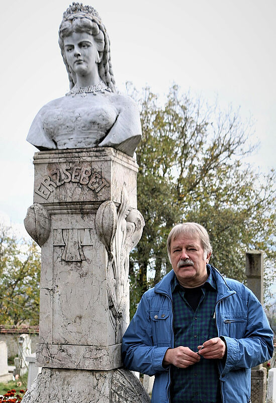 Konrad Klein neben einem Denkmal von Kaiserin ...