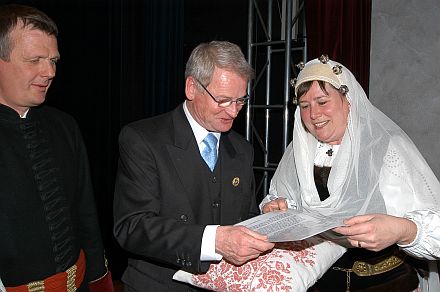 Doris Hutter berreicht Klaus-Peter Gbelein Kissen und Authentizittszertifikat. Links im Bild – ebenfalls in Agnethler Tracht – Georg Hutter. Foto: Karl Schuster