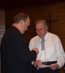 Der Vorsitzende der Kreisgruppe Crailsheim, Friedrich Wegendt (links), berreicht das goldene Ehrenwappen an Chorleiter Matthias Pelger. Foto: C. Klein