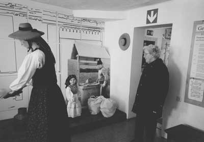 Der erste Raum des Landlermuseums in Bad Goisern zeigt eine angedeutete Dorfstrae in Neppendorf. An der Stelle der kartenlegenden Zigeunerin befindet sich heute ein kleines Landlermdchen (Bildmitte). Rechts im Bild die Heimatpflegerin und ehrenamtliche Helferin Elfriede Zwanzleitner. Foto: Konrad Klein.