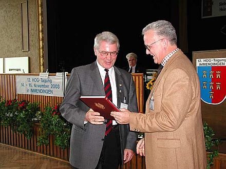 Bundesvorsitzender Volker Drr (rechts) wrdigt den ehemaligen Vorsitzenden des HOG-Verbandes, Horst Gbbel, mit einem Buchprsent. Foto: Gnther Melzer.