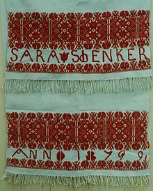 Kirchenhandtuch, Hausleinwand, 46 x 180 cm. Rot eingewebte Stern- und Nelkenbordren, aufgestickter Name und Jahreszahl, gedrehte Fransen mit Kntchenabschluss an beiden Enden. Arkeden, 1879.